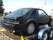 1987 Ford Mustang - This black 1987 Ford Mustang coupe is seen from the rear 3/4 angle, appearing to be in a state of repair or modification.