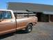 1979 Ford F-150 - A brown 1979 Ford F-150 pickup truck with wooden bed rails is parked in front of a building.