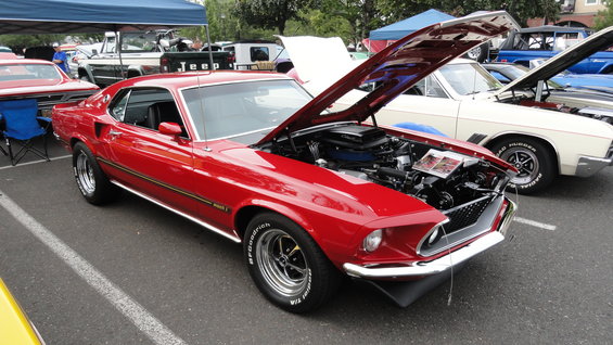 red 1969 Mustang Mach 1 with hood open, parked next to other cars