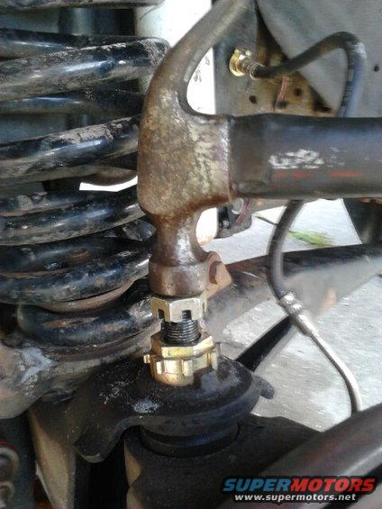With a hammer, hit the ball joint straight down flush with the nut. When you hit it down you will see the stud go down and in my case will even pop the bushing loose and up on its own. I hit it till the stud wouldnt go down any more and the bushing wouldnt come up anymore. 

This process pervents breaking the bushing by using a chissle to hit it up. the alignment shops around me ALWAYS break the little tabs off the bushing becuase of this.

Since my bushing was freshly installed it was easy to take out. Others that have been in for a while might need alittle help with channellocks or hammer and chissle anwyays but be carefull not to damage the bushing, the tabs break off easily.