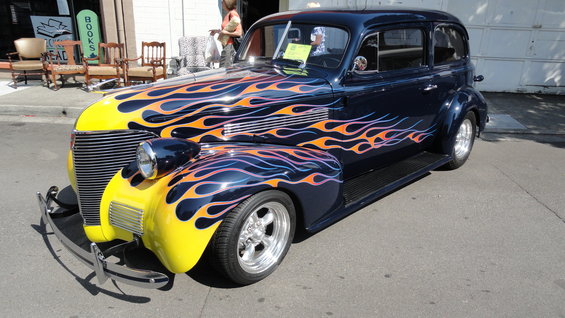 Dark blue sedan with yellow front fenders and orange and purple flame graphics, seen from a 3/4 front angle