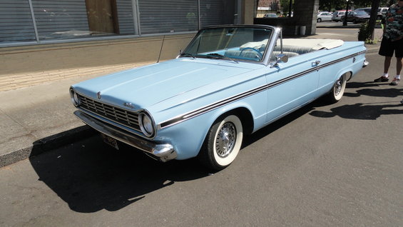 Light blue convertible parked on street, top down. Whitewall tires and chrome trim visible