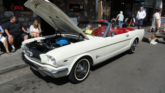 White 1965 Ford Mustang convertible with red interior, hood open showing engine