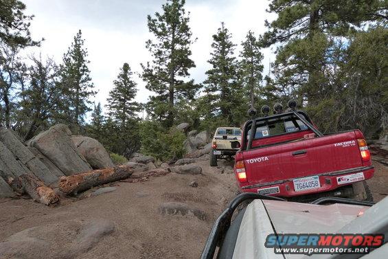 Red Toyota Tacoma pickup truck, rear view, off-roading