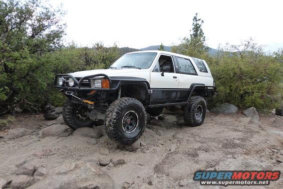 1985 Toyota 4Runner on a rocky trail, modified with large tires and a brush guard