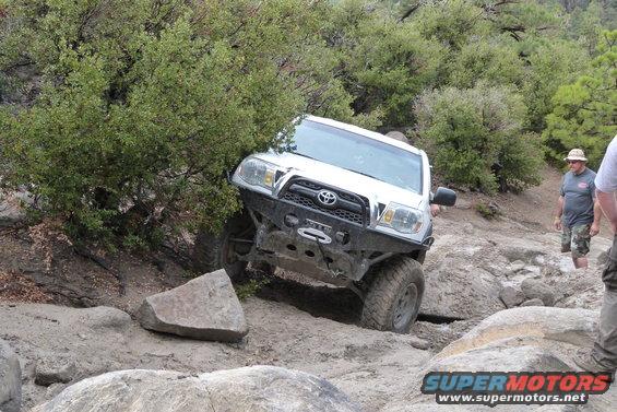 White Toyota 4Runner navigating a rocky off-road trail. Visible text: SUPERMOTORS.NET