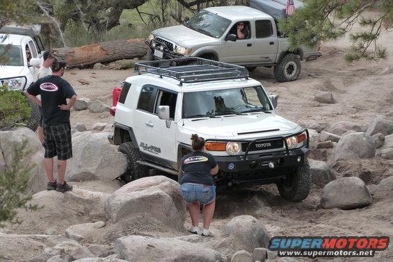 White Toyota FJ Cruiser navigating rocks with a silver Toyota Tacoma behind it
