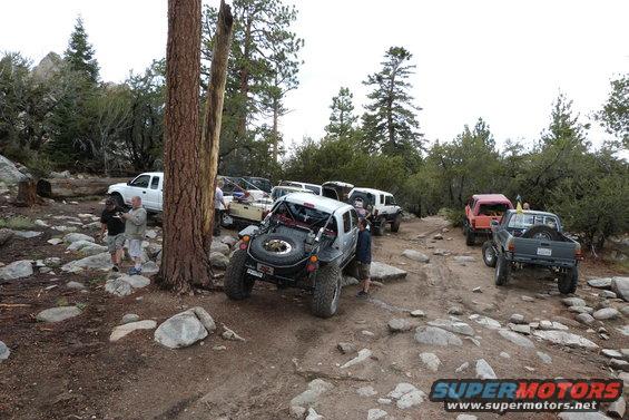 Several off-road vehicles gathered on a rocky mountain trail