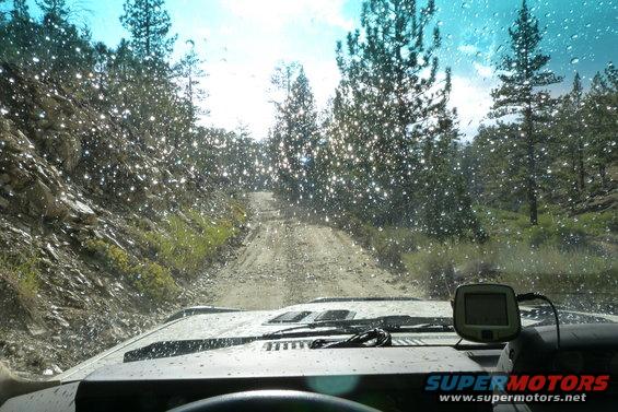 Interior view of a vehicle on a dirt road, GPS unit on dashboard