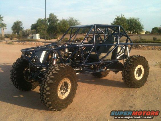 Blue tube-frame off-road buggy with large tires and exposed engine components