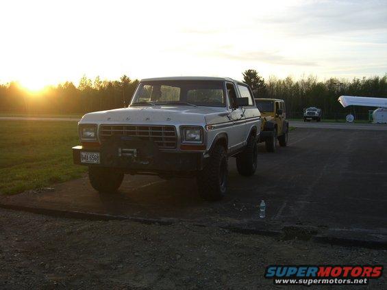 White 1979 Ford Bronco with winch, parked next to a yellow Jeep