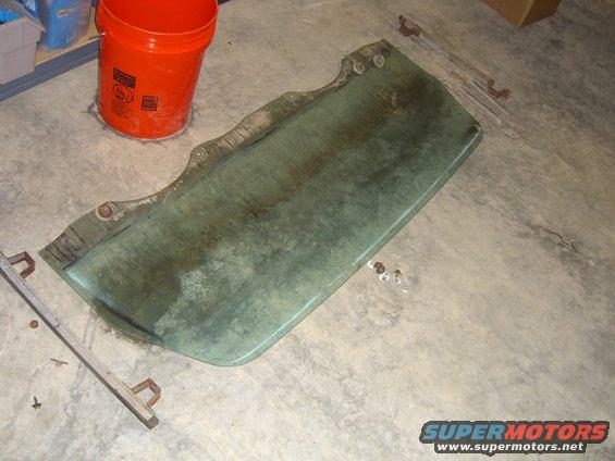 green car door on concrete floor next to orange bucket