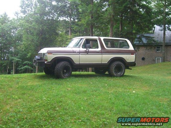 Two-tone brown and cream 1978 Ford Bronco with off-road tires parked on a grassy hill