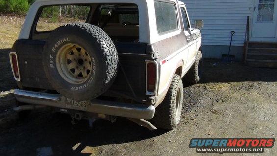 Rear view of a white and brown Ford Bronco with a spare tire mounted on the back. License plate reads AX 6568