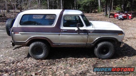 Side view of a two-tone brown and white Ford Bronco with a spare tire on the back
