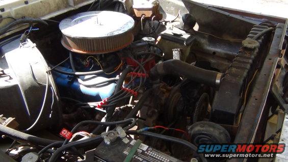 Engine bay with air cleaner, radiator, battery, and wiring visible