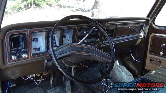 1979 Ford Bronco interior dashboard with wood grain trim, black steering wheel, and analog gauges