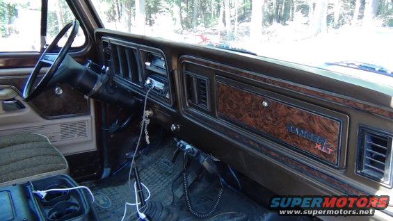 Interior shot of a 1979 Ford Bronco showing the dashboard with wood grain trim and 'Ranger XLT' badging