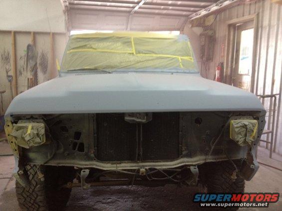Front view of a 1979 Ford Bronco with hood and windshield taped off for paint