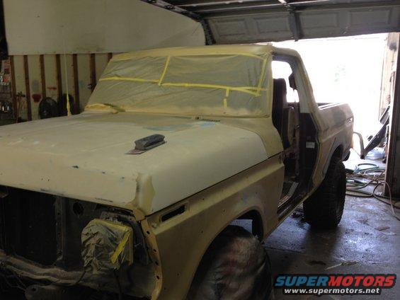 Yellow Ford Bronco in garage, masked for paint, with sanding block on hood