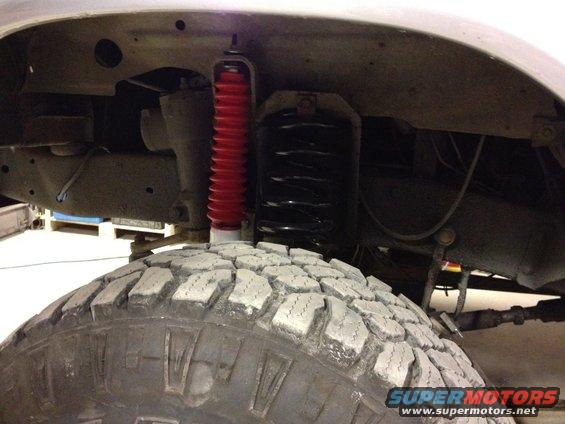 Close-up of a large off-road tire and red shock absorber on a vehicle's suspension