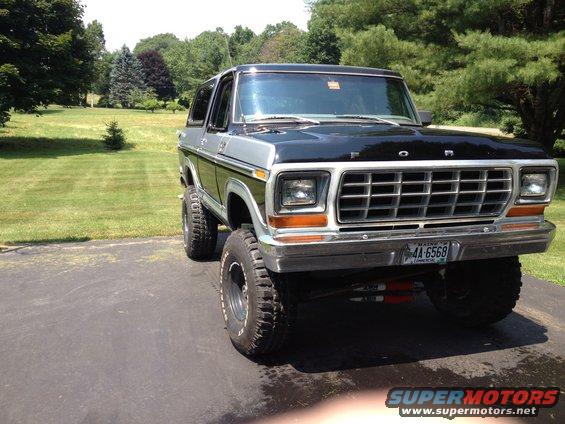 Lifted Ford Bronco with black hood and silver top, parked on driveway