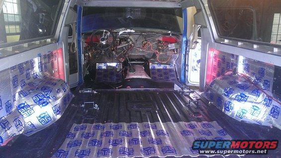 Interior of a vehicle with soundproofing material applied to the floor and side panels. Dashboard and steering wheel are visible