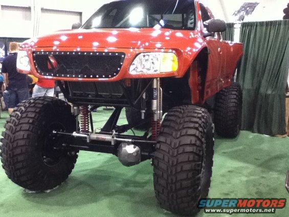 Red lifted truck with oversized tires and custom grille