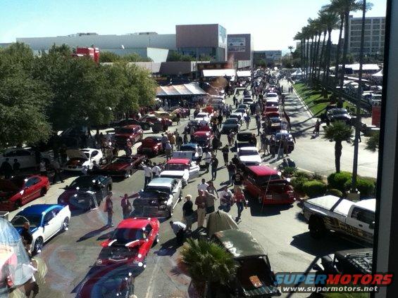 Street filled with cars and people at an outdoor event