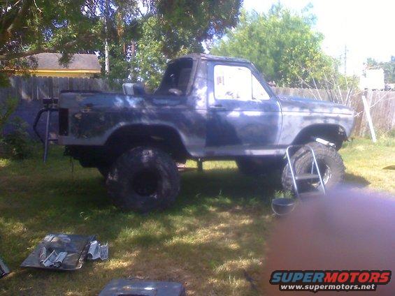Ford Bronco with large tires, missing some body panels, parked in a yard