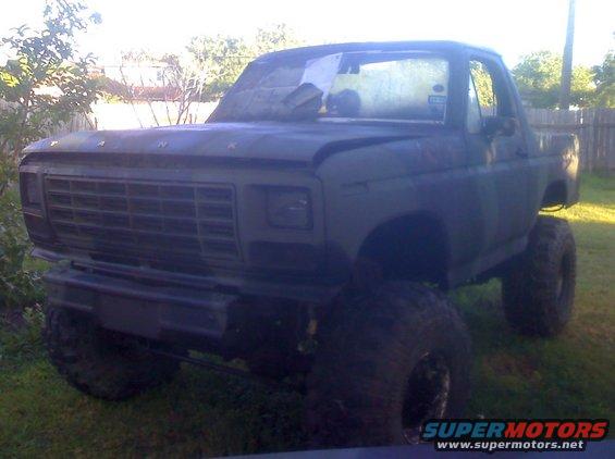 Lifted dark green truck, front view, large tires, aftermarket grille