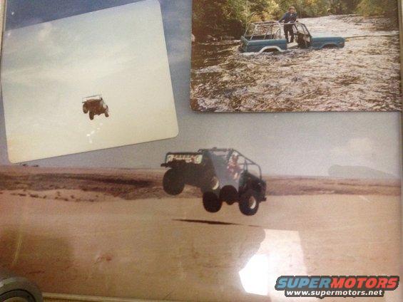 Off-road vehicle mid-air jump. Another vehicle is partially submerged in water in the background
