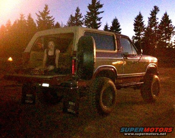 Maroon and tan Ford Bronco with lifted suspension and spare tire on the back