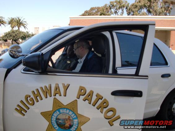 Side view of a white California Highway Patrol car interior with two men, door open