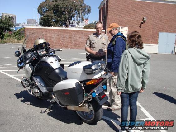 Police motorcycle with saddlebags and a helmet on the handlebars, parked in a lot
