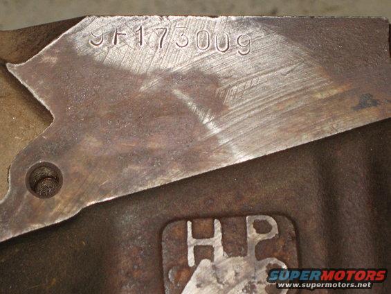 Close-up of a metal engine part with the stamped serial number 9F175009 and an HP marking