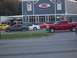 1970 Ford Ranchero - A red pickup truck is seen driving on the road in front of a restaurant.