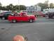 1970 Ford Ranchero - A red 1965 Ford F-100 pickup truck is seen driving down the road with other vehicles.