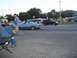 1970 Ford Ranchero - A blue convertible cruises down the street with other vehicles and pedestrians present.