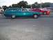 1970 Ford Ranchero - A teal station wagon drives down the road next to a red sports car.