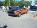 1970 Ford Ranchero - This orange and black convertible muscle car features bold racing stripes and a prominent hood scoop, suggesting a powerful performance mod…