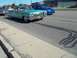 1970 Ford Ranchero - A teal 1960s Cadillac convertible cruises down the road with a blue Subaru following.