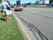 1970 Ford Ranchero - A classic red Camaro convertible cruises down the road while onlookers observe from the grassy shoulder.
