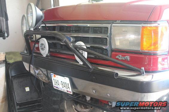 Red 1990 Ford Bronco front end with a chrome grille, auxiliary lights, and a custom light bar