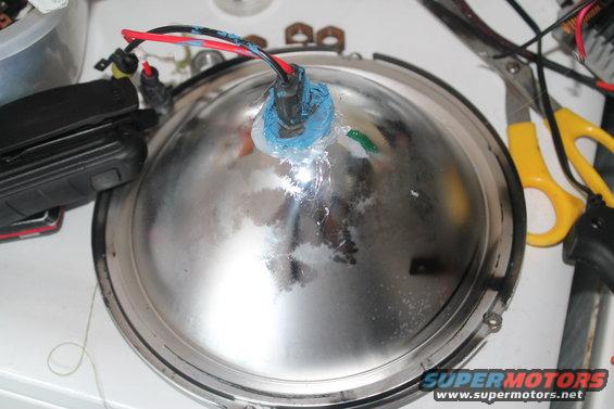 Close-up of a chrome automotive headlight assembly with wires attached