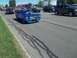 1970 Ford Ranchero - A custom blue coupe with a prominent hood scoop drives down a street in a parade.