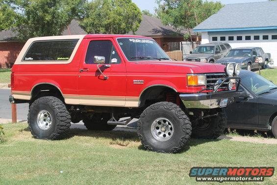 Red lifted 1990 Ford Bronco with tan trim and off-road lights