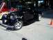 1970 Ford Ranchero - This black 1930s pickup truck is parked outdoors with other vehicles and an orange cone.
