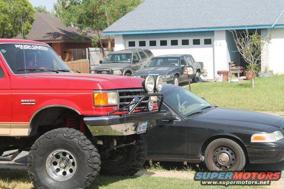 Lifted red Ford Bronco next to a black sedan in a driveway