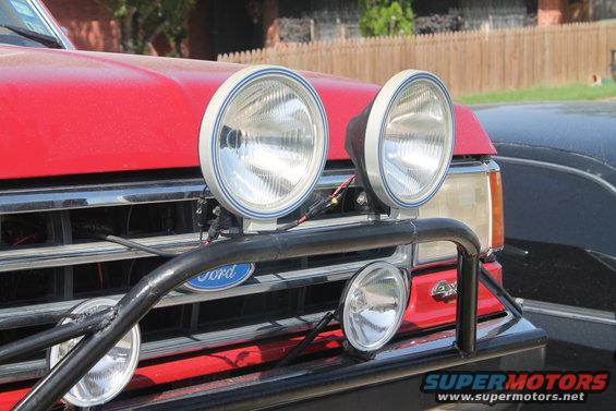 Red Ford Bronco front grille with two large auxiliary lights mounted on a black bull bar